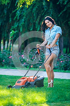 Woman mowing lawn in residential back garden