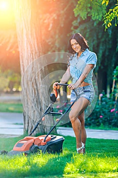Woman mowing lawn in residential back garden on