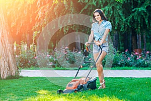 Woman mowing lawn in residential back garden