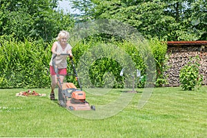 Woman mows the grass in the garden