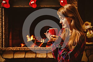 Woman with a mug by the fireplace. Young attractive woman sittin