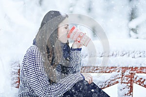 woman with mug of hot drink in winter park
