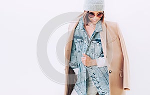 Woman in multilayered autumn outfit: camel coat, denim jacket an