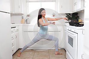 Woman multitasking while cooking, preparing meal, exercising yoga and stretching in the kitchen to save time