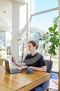 Woman Multitasking with Smartphone and Laptop at Cafe