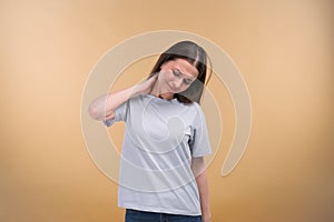Woman with muscle injury having pain in her neck - body pain portrait shot on a beige background