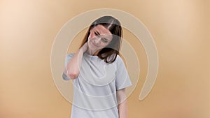 Woman with muscle injury having pain in her neck - body pain portrait shot on a beige background