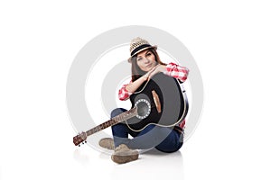 Woman musician with guitar sitting on floor.