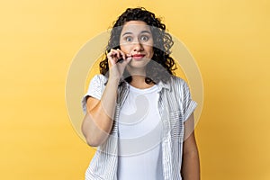 Woman with mystery look making zip gesture to close mouth, keeping secret, zipping lips.