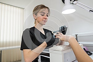 A woman in a nail salon getting a manicure by a cosmetologist with a nail file