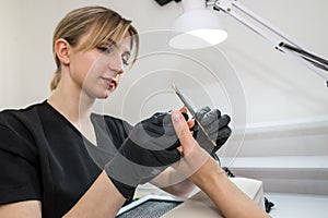 A woman in a nail salon getting a manicure by a cosmetologist with a nail file. Woman gets a manicure of nails