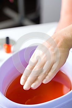 Woman in nail salon having paraffin bath photo