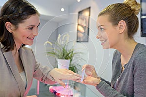 Woman in nail salon receiving manicure by beautician