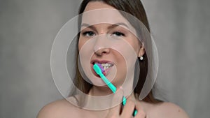Woman naked cleans her teeth with toothbrush and paste after shower.