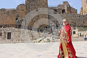 A woman in the national costume of the Bedouin nomads in Jordan during the Crusaders times against the backdrop of the fortress w