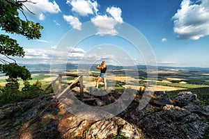 Woman near bench with beautiful view on summer countryside on hill called Ondrasovska skala, Slovakia