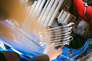 Woman near car`s hood. young blonde in covered parking of shopping center, stands near car with engine compartment bonnet raised,