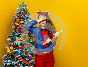 Woman near Christmas tree holding unwanted present