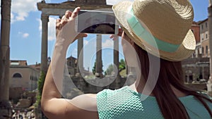 Woman near Forum Romanum taking photo on mobile phone. Female tourist taking picture of Roman forum