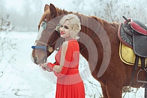 Woman near a horse in the winter forest