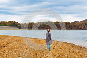 Woman near lake at Autumn season enjoying view of beautiful for