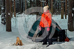 woman near a tent at a camping site in a winter forest