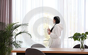 Woman near window in room decorated with plants. Home design