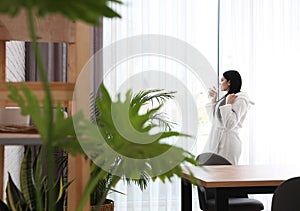 Woman near window in room decorated with plants. Home design