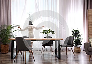 Woman near window in room decorated with plants. Home design