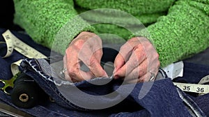 Woman with needle and thread and denim fabric