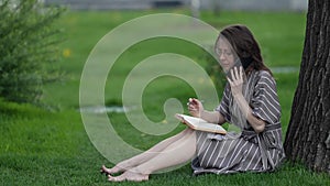 woman is negotiating by mobile phone during break or holiday in park at summer day