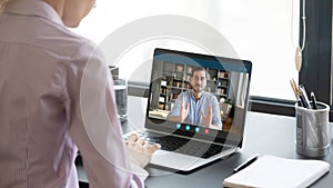 Woman negotiating via internet using laptop, view over female shoulder