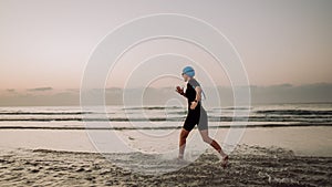 Woman in neoprene running along of the ocean.
