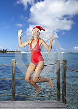 The woman in New Year's Santa-Klaus cap on background of sea jumps