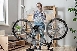 Woman next to a bicycle is showing two thumbs up. Concept of maintenance and preparation of the bike for the new season