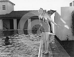 Woman next to a pool in her swimming cap and bathing suit