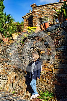 Woman next to a stone wall enjoying the sun in the village of Patones de Arriba. photo