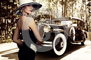 Woman in nice dress and hat against retro car