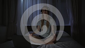 A woman at night turns on a meditation, relaxation application on her computer to relax before going to bed. Antistress