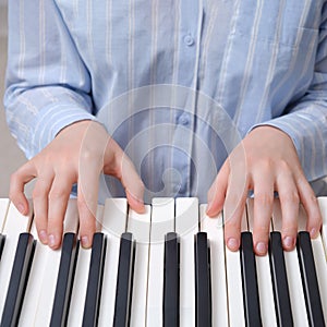 A woman in a nightgown plays an electric piano, hands close-up