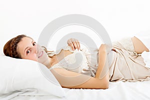 Woman in nightrobe lying on bed at bedroom