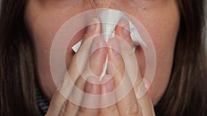 Woman with nose reddened from illness snots in napkin macro