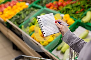 Woman with notebook in grocery store, closeup. Shopping list on paper.