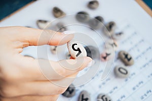 Woman numerologist hand with pebble stone with number five 5.