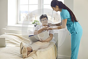 Woman nurse giving prescribed pills and glass of water to happy elderly lady