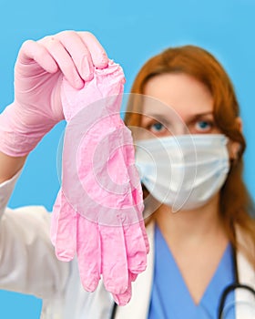 Woman nurse with medical gloves on a blue background, face closeup