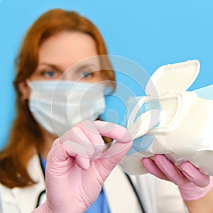 Woman nurse in medical mask with cleaning wipes on a blue background, close-up face