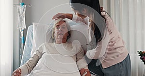 Woman, nurse and patient in elderly care on bed for healthcare, support or rest at the hospital. Female volunteer