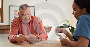 Woman, nurse and senior patient playing cards on table for fun game time or activity at old age home. Female person