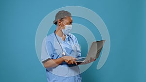 Woman nurse wearing face mask and using laptop